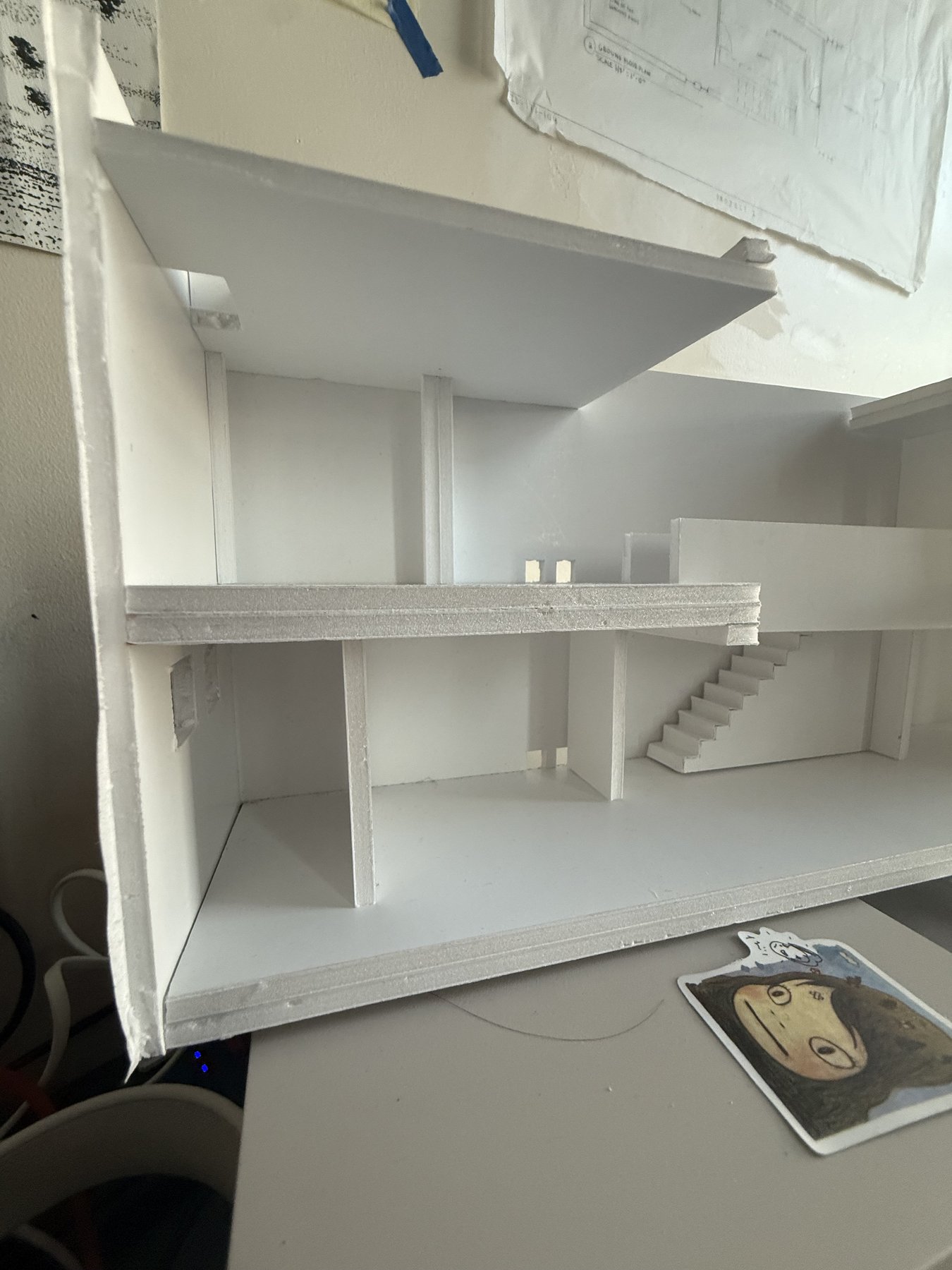 Physical model on the studio desk, shown alongside the working drawings pinned to the wall behind it.