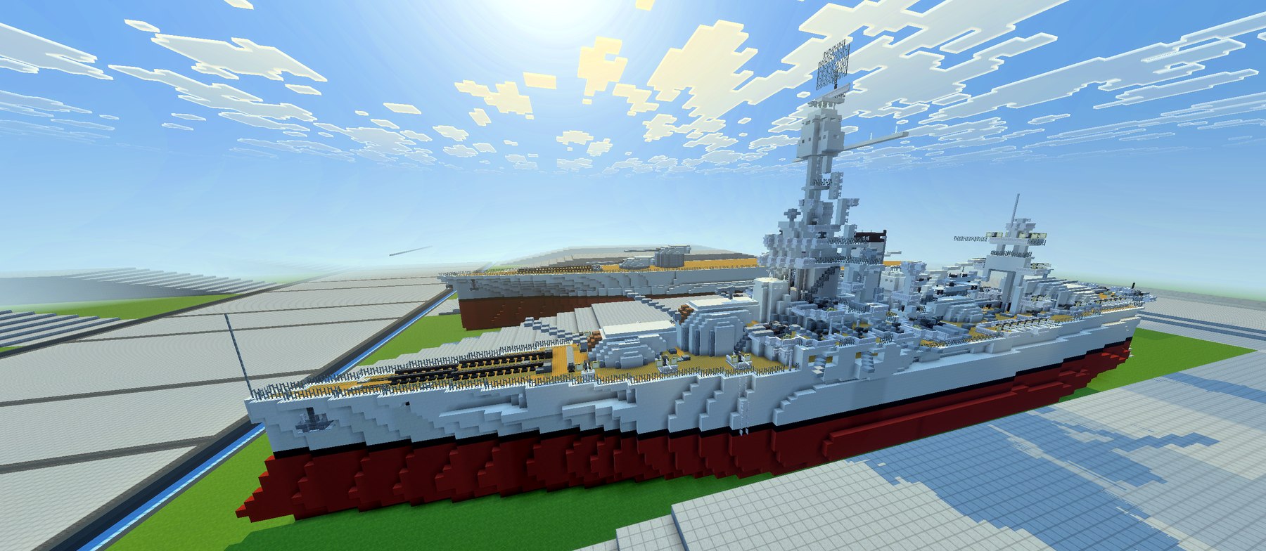 Full profile view of USS New York with the cage mast backlit by the sun.