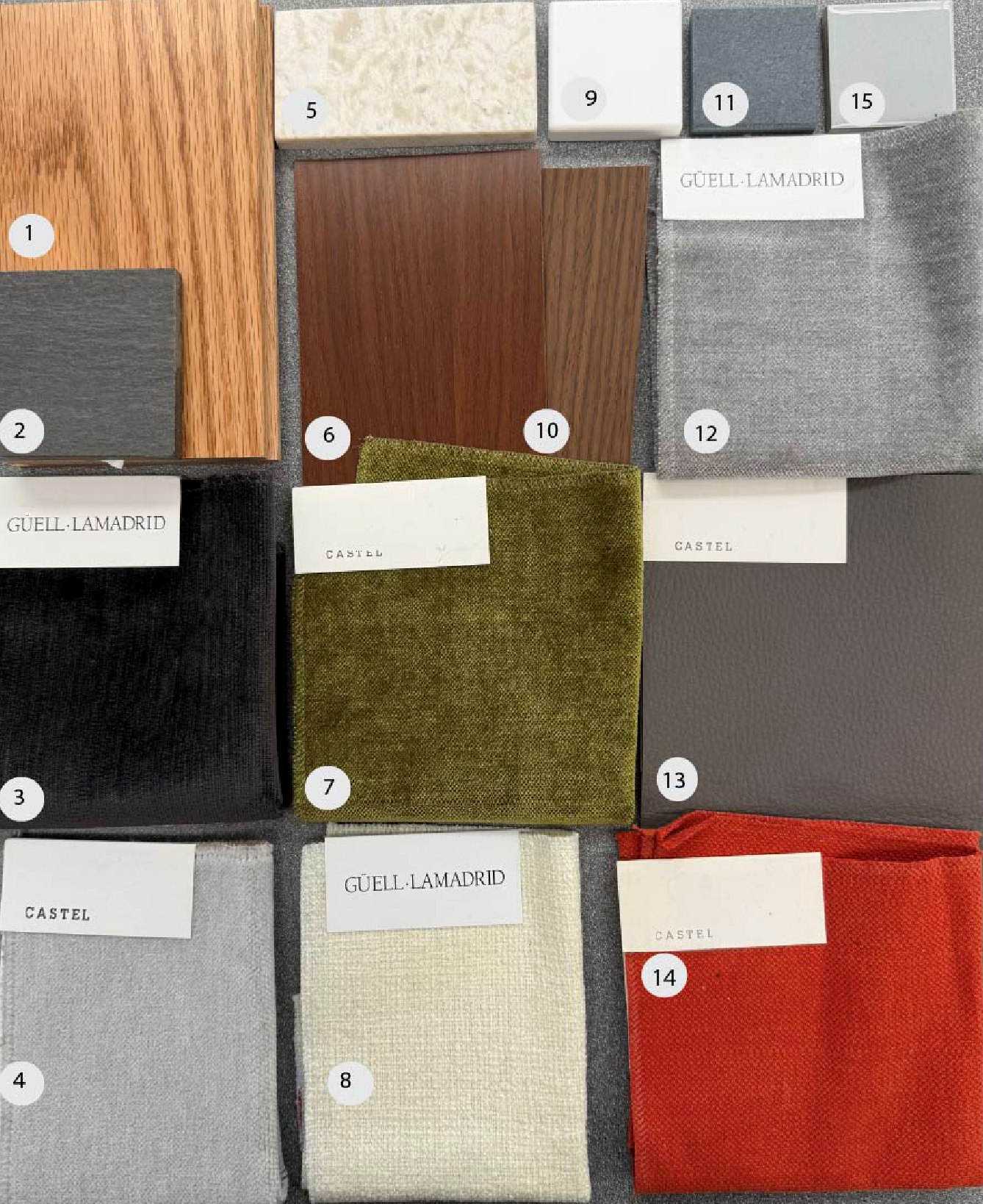 Photo of the physical materials board with fifteen numbered samples: wood, tile, stone and upholstery fabrics.